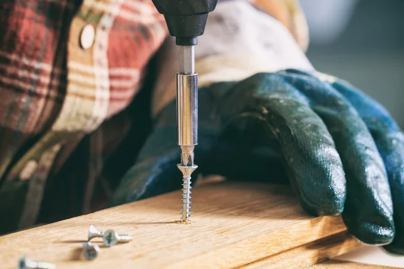 Person schraubt Holzbrett fest